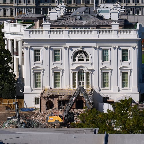 Construction workers atop the U.S. Treasury, bottom right, watch as work continues on a largely demolished part of the East Wing of the White House, Thursday, Oct. 23, 2025, in Washington, before construction of a new ballroom. (AP Photo/Jacquelyn Martin)