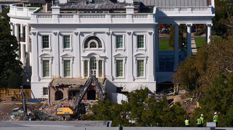 Construction workers atop the U.S. Treasury, bottom right, watch as work continues on a largely demolished part of the East Wing of the White House, Thursday, Oct. 23, 2025, in Washington, before construction of a new ballroom. (AP Photo/Jacquelyn Martin)