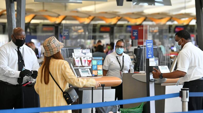 Travelers wearing face masks check in through plexiglass dividers at Delta counters at Hartsfield-Jackson International Airport on Thursday, July 2, 2020.(Hyosub Shin /Hyosub.Shin@ajc.com)