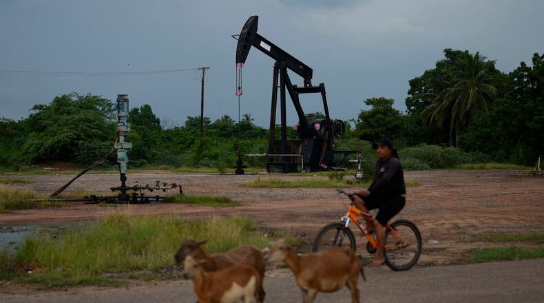 A man rides past an operating oil pumpjack in Cabimas, Venezuela, Monday, Aug. 31, 2026. (AP Photo/Ariana Cubillos)