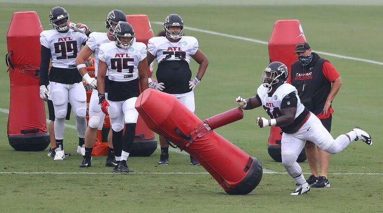 Falcons defensive tackle Deadrin Senat (right) levels a tackling dummy running drills during training camp on Saturday, Aug. 22, 2020, in Flowery Branch. (Curtis Compton ccompton@ajc.com)