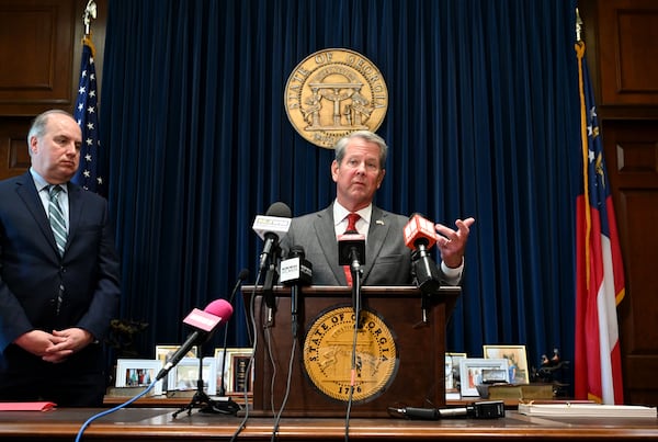 Gov. Brian Kemp (center) speaks before signing the state’s new budget on Tuesday alongside Rick Dunn, director of the Governor’s Office of Planning and Budget. (Hyosub Shin/AJC)