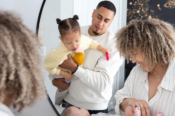 Brandon Chambers and Lola, 2, watch as Lauren Chambers changes Hayden, six months, at their home in Smyrna on Monday, May 5, 2025. (Arvin Temkar/AJC)