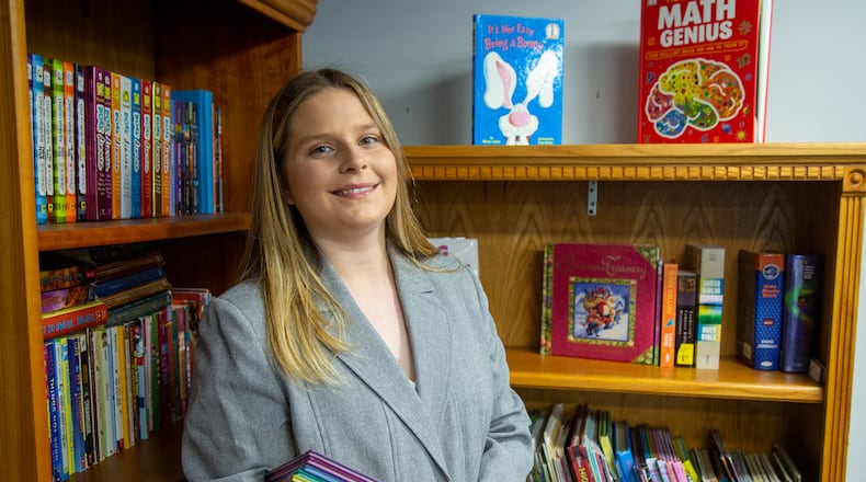 Josie Dunlap stands with some of the books she stocked in the resource room at Eastside Mosaic Church in Marietta. As a Girl Scout, she established three permanent micro libraries for kids in areas that are book deserts. One of the Book Nooks is at Eastside Mosaic Church community and resource center where students did their virtual classes during the pandemic. Josie stocked the room with 900 books, plus games and school supplies. This is Josie's Girl Scout Gold Award project. PHIL SKINNER FOR THE ATLANTA JOURNAL-CONSTITUTION.