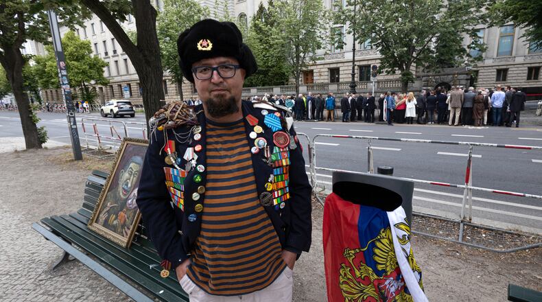 A man identified by Polish media as Robert Kuzovkov and by prosecutors as Robert K., in accordance with Polish privacy law, who they said was an artist who used the pseudonym Semyon Skrepetsky, poses for a photo with one of his paintings near the Russian Embassy in Berlin, Germany, on Friday, June 12, 2026, four days before Polish authorities said he was shot and killed in Biala Podlaska, Poland. (Vasily Krestyaninov/SOTA via AP)