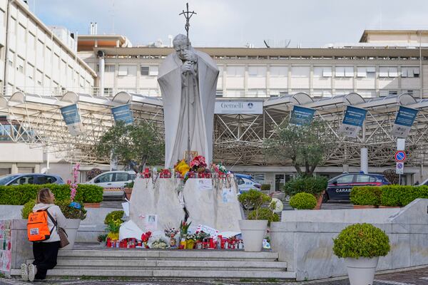 Samantha Brasini, of Italy, kneels in front of the statue of Pope John Paul II as she prays for Pope Francis outside the Agostino Gemelli polyclinic in Rome, Italy, Sunday, March 16, 2025. (AP Photo/Gregorio Borgia)
