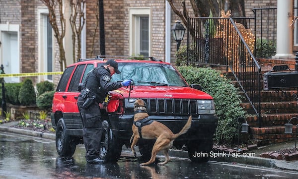 A Brookhaven police dog and his handler conduct a search of a Jeep Cherokee parked outside a home on Hedge Rose Court. Detectives searched the home for narcotics, according to police. JOHN SPINK / JSPINK@AJC.COM