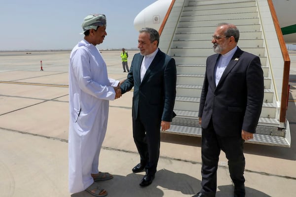 In this photo released by the Iranian Foreign Ministry, Iranian Foreign Minister Abbas Araghchi, center, is welcomed by an unidentified Omani official upon his arrival at Muscat, Oman, for negotiations with U.S. Mideast envoy Steve Witkoff, as Iranian Ambassador to Oman Mousa Farhang stands at right, Sunday, May 11, 2025. (Iranian Foreign Ministry via AP)