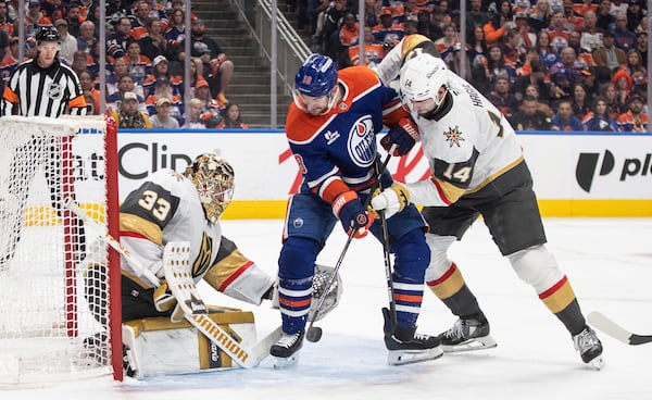 Vegas Golden Knights goalie Adin Hill (33) makes a save against Edmonton Oilers' Zach Hyman (18) as Golden Knights' Nicolas Hague (14) defends during the second period of Game 4 of a second-round NHL hockey playoff series in Edmonton, Alberta, Monday, May 12, 2025. (Jason Franson/The Canadian Press via AP)