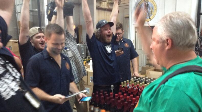 Brad Durham pays for a tour and gets three bottles of souvenir beer at Burnt Hickory Brewery in Kennesaw just after the stroke of midnight on July1. (Holly Steel /hsteel@ajc.com)