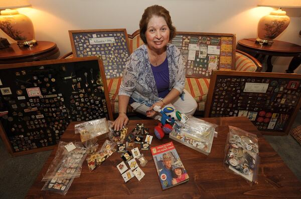 Francis Carey sits on her sofa surrounded by some of her over 1,800 Olympic pins. She got the collecting bug during the 1996 Olympics.