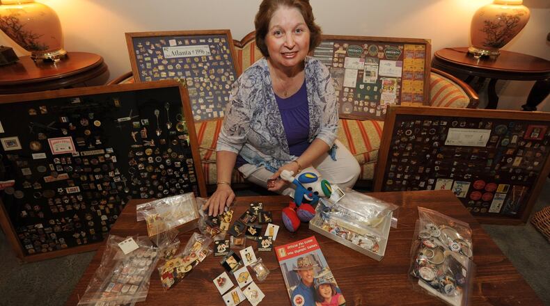 Francis Carey sits on her sofa surrounded by some of her over 1,800 Olympic pins. She got the collecting bug during the 1996 Olympics.