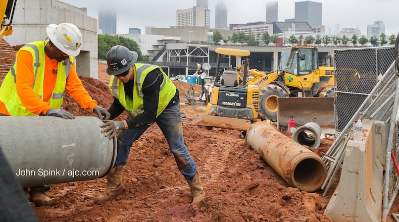 Fog covers Atlanta as Reeves and Young Construction workers Joseph Jackson, left, and Tom Palmer put piping into place at the Home Depot Backyard next to Mercedes Benz Stadium.
