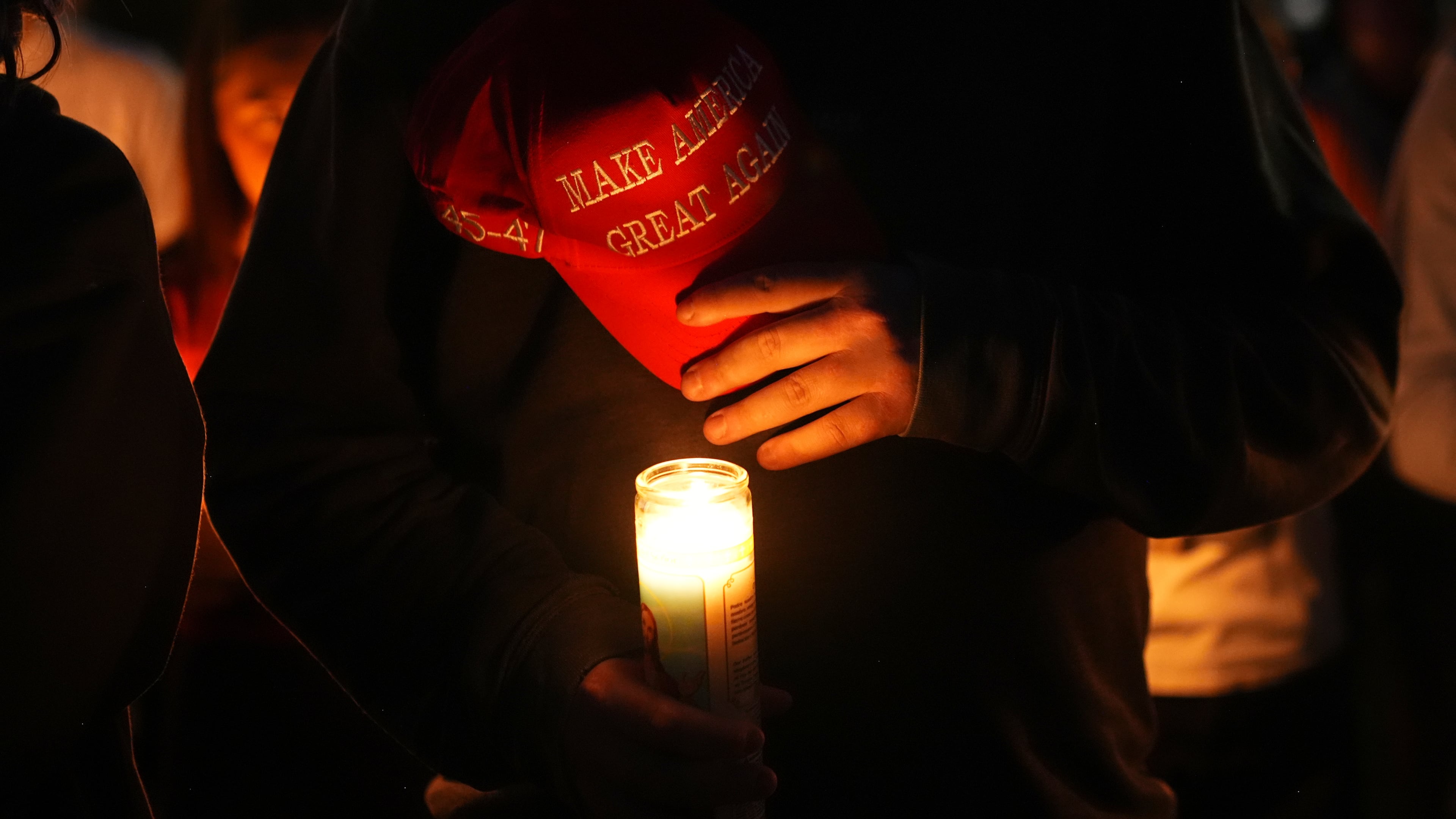 Alex Thomson holds a "Make America Great Again" hat during a vigil for Charlie Kirk on Friday, Sept. 12, 2025, in Provo, Utah. (AP Photo/Lindsey Wasson)