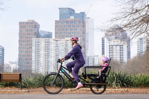 A woman and child ride an e-bike through Piedmont Park amid unusually warm weather on Wednesday, Jan. 7, 2026, in Atlanta. (Ben Hendren for the AJC)