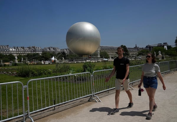 People walk past the Olympic cauldron at the Tuileries Gardens, ahead of its nightly summer relaunch starting June 21, in Paris, Thursday, June 12, 2025. (AP Photo/Michel Euler)
