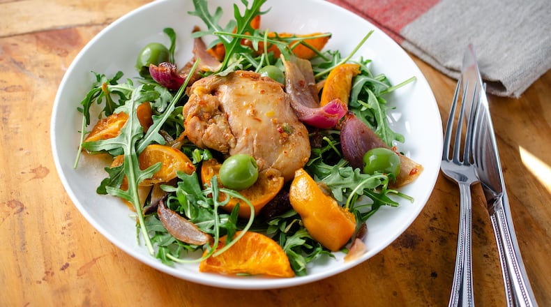 Tender boneless, skinless chicken thighs combined with spicy harissa, sweet honey, thinly sliced clementines, zesty red onion and buttery green olives are served atop arugula. (Virginia Willis for The Atlanta Journal-Constitution)
