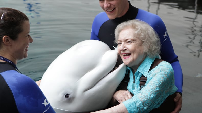 Betty White gets a kiss from Beethoven, the beluga whale, at Georgia Aquarium. She's joined by trainers Dennis Christen and Trish Dove.