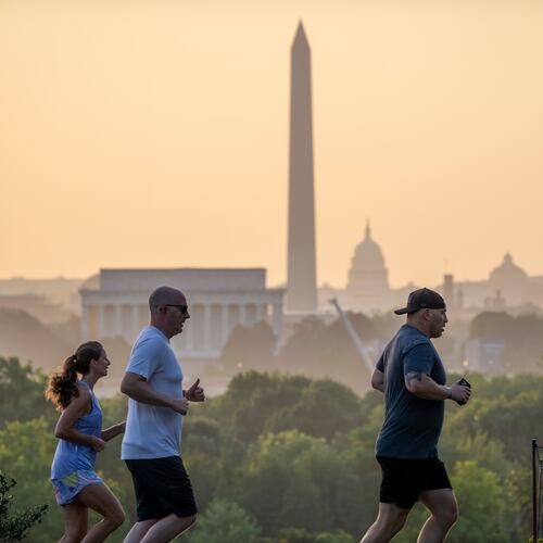 The Lincoln Memorial, Washington Monument, and U.S. Capitol are seen at dawn as joggers run past an overlook in Arlington, Va., Friday, July 3, 2026. (AP Photo/J. Scott Applewhite)