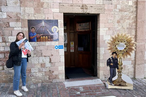 Amelia Simone, 18, a student from the United States, stands in front of the entrance of the Santa Maria Maggiore Church where the body of the 15-year-old Italian boy Carlo Acutis, who died in 2006 and was beatified in 2020, is kept, in Assisi, Italy, Wednesday, April 2, 2025. (AP Photo/Alessandra Tarantino)