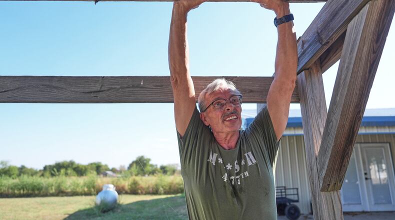 Ed Westrick, 59, adjusts a roof on a small building at his rural home near Commerce, Texas, Friday, Sept. 18, 2026. (AP Photo/LM Otero)