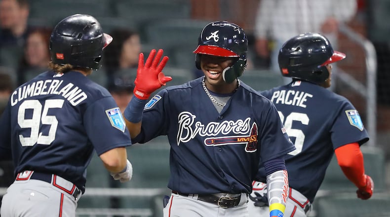Braves' Ronald Acuna Jr. gives outfielder Cristian Pache (right) and Brett Cumberland (left) high fives at home plate after Pache hit a 2-run homer off pitcher Sean Newcomb.  Curtis Compton/ccompton@ajc.com
