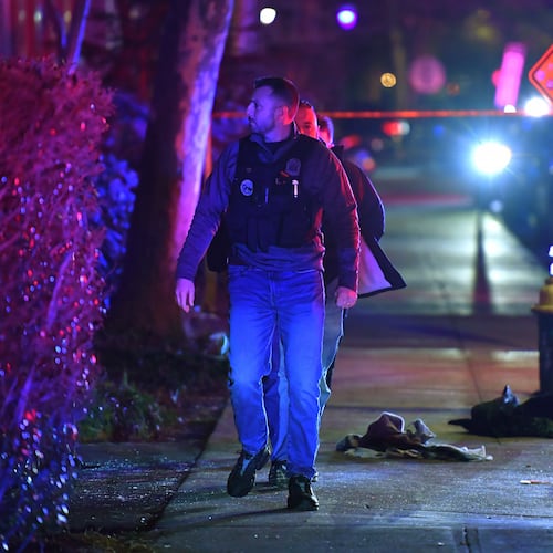 A law enforcement official walks past articles of clothing on a sidewalk near an entrance to Brown University, Saturday, Dec. 13, 2025, in Providence, R.I., during the investigation of a shooting. (AP Photo/Steven Senne)