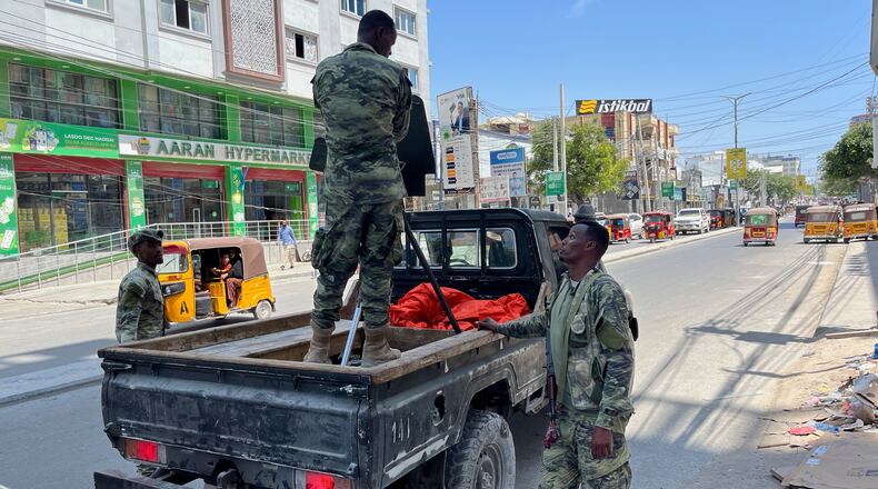 A Somali National Army (SNA) soldier stands in the back of a pickup truck as others stand nearby on a street in Mogadishu, Somalia, Monday, Nov. 10, 2025. (AP Photo/Rodney Muhumuza)