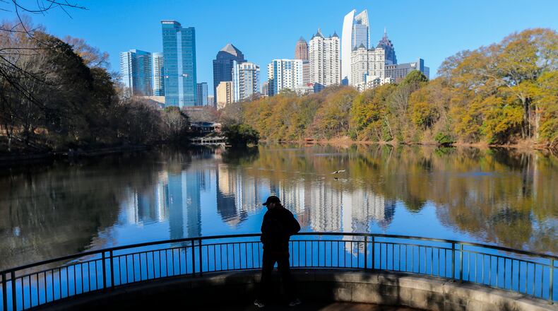 A man looks at the view of the Atlanta skyline reflected in Lake Clare Meer at Piedmont Park in December 2016.
