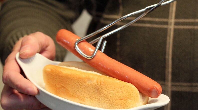 JANUARY 25, 2013-SUWANEE: Chris Schutte plates a hotdog on a bun steamed by his latest product in the kitchen of his Suwanee home on Friday Jan. 25th, 2013. When he lost his job a second time, he decided to scratch a long standing itch and become an entrepreneur. His idea: a kitchen cooking device he'd conceived called the Hot Dog Bun EZ Steamer - a contraption made out of wire that you stick in a pot and perfectly steams the bun while cooking the dog. Before he knew it, his crazy idea seemed to be taking off. But sales fell short. One low point found him taking back tens of thousands of Steamies from QVC when it couldn't sell them. Schutte hasn't given up. But he knows the time to make his dream come true may be coming to an end. PHIL SKINNER / PSKINNER@AJC.COM editor's note: CQ