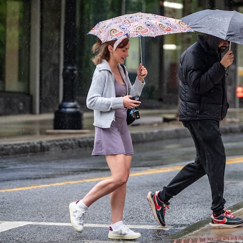 Rain is in the forecast for metro Atlanta on Tuesday, which experts predict will be one of the busiest road travel days of the Thanksgiving week. A man and woman with umbrellas walk along Peachtree Street in downtown Atlanta in April. (Ben Hendren for the Atlanta Journal-Constitution)