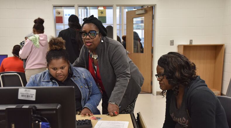 Standrine Francia (center), financial aid advisor, helps Myeshia Barrett, 18, and her mother Ieshia Barrett (right) as Myeshia Barrett fills out application for Federal Student Aid during Achieve Atlanta FAFSA Clinic at Therrell High School in Atlanta in this 2018 file photo.
