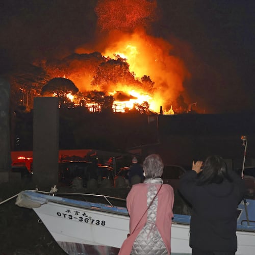 Residents watch flames rise from the site of a fire in Oita, southern Japan Tuesday, Nov. 18, 2025. (Kyodo News via AP)