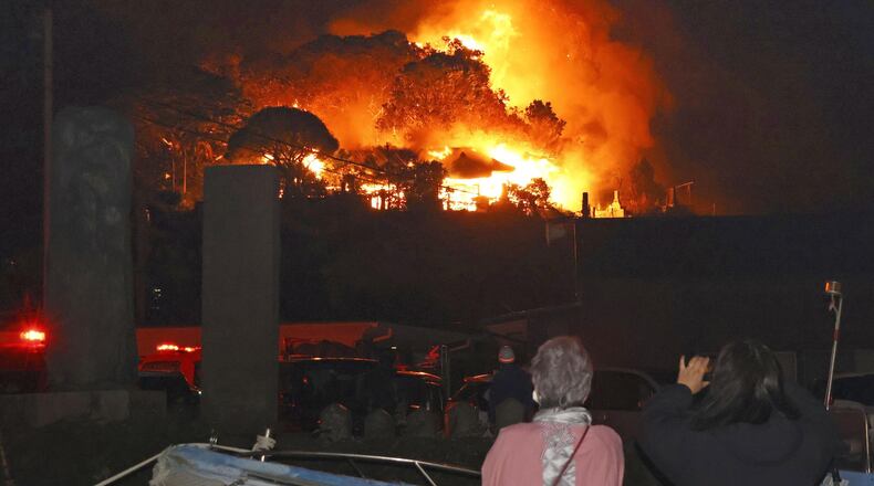 Residents watch flames rise from the site of a fire in Oita, southern Japan Tuesday, Nov. 18, 2025. (Kyodo News via AP)