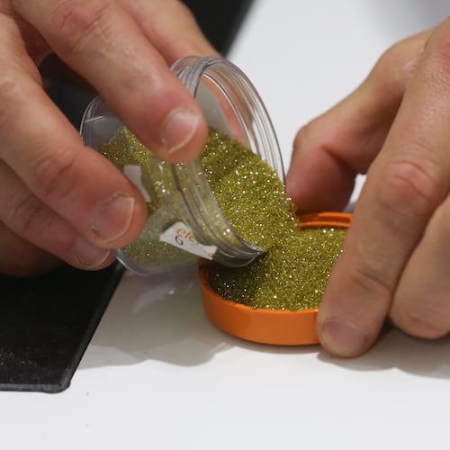 An employee pours out synthetic diamond grit at inside De Beers Element Six laboratory in Didcot, U.K., on Tuesday, June 30, 2015. About 360,000 carats of man-made gems were produced last year, compared with 126 million carats of natural diamonds. Photographer: Chris Ratcliffe/Bloomberg via Getty Images