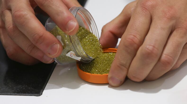 An employee pours out synthetic diamond grit at inside De Beers Element Six laboratory in Didcot, U.K., on Tuesday, June 30, 2015. About 360,000 carats of man-made gems were produced last year, compared with 126 million carats of natural diamonds. Photographer: Chris Ratcliffe/Bloomberg via Getty Images