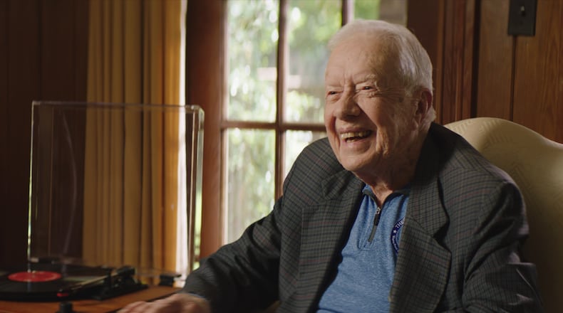 Former president Jimmy Carter smiles as he listens to an old LP.