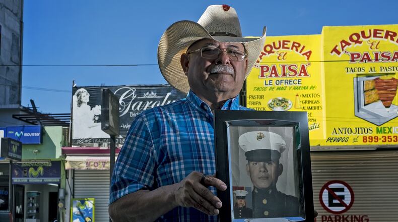 Jose Martinez, a former Marine and Vietnam war veteran, holds a framed portrait of himself taken during his Marine boot camp outside of his mobile phone store in Nuevo Progreso, Mexico, on Wednesday, Feb. 24, 2016. RODOLFO GONZALEZ / AUSTIN AMERICAN-STATESMAN