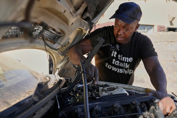 Themba Maseko, a 39-year-old mechanic, repairs a BMW car outside his workshop in Brakpan, east of Johannesburg, South Africa, Wednesday, May 14, 2025. (AP Photo/Themba Hadebe)