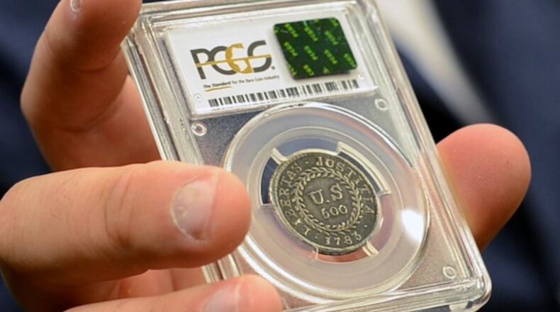 In this Monday, July 31, 2017, image made from a video, David McCarthy, a senior numismatist at Kagin's, holds what is believed to be the first coin ever struck by the U.S. government at the World's Fair of Money in Denver, Colo. The coin is on display this week at the World's Fair of Money. (AP Photo/Tatiana Flowers)