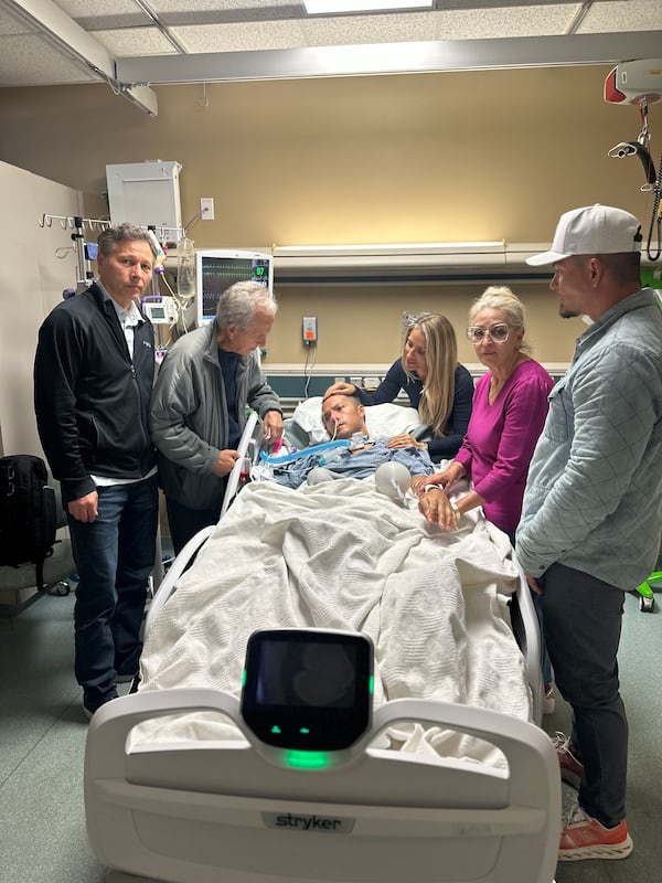 Mark Moczarski is surrounded by his parents and siblings after he was flown back to metro Atlanta following a moped crash in Bali last month. (Courtesy Moczarski family)