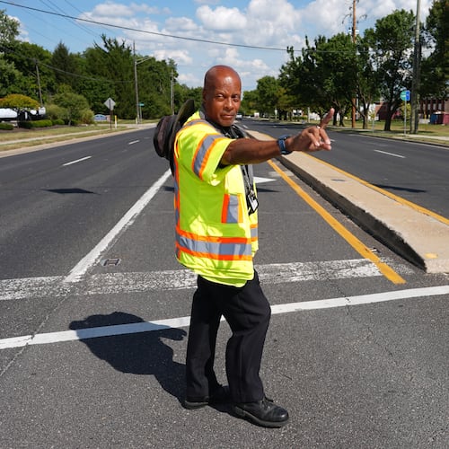 School crossing guard Anthony Taylor directs students on when to cross the street, Wednesday, Sept. 3, 2025, in Indianapolis. (AP Photo/Darron Cummings)