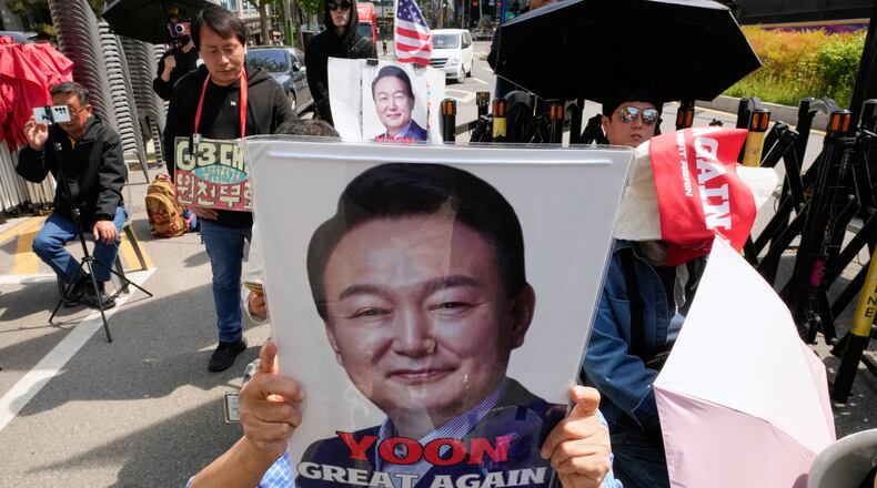 A supporter of former South Korean President Yoon Suk Yeol holds up his portrait during a rally outside of the Seoul High Court in Seoul, South Korea, Wednesday, April 29, 2026. (AP Photo/Ahn Young-joon)