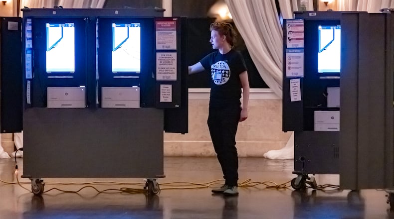 Poll worker, Gamble Everett prepares machines in the voting area before the polls opened to nearly no one voting at the polling place at the Park Tavern located at 500 10th Street NE in Atlanta on Tuesday, March 12, 2024. (John Spink / John.Spink@ajc.com)