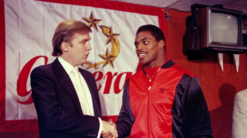 Donald Trump shakes hands with Herschel Walker in New York in March 1984 after agreement on a 4-year contract with the New Jersey Generals USFL football team. (AP Photo/Dave Pickoff, File)