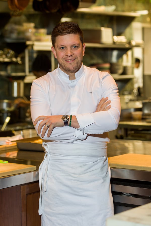 Freddy Money stands smiling in front of a restaurant kitchen.