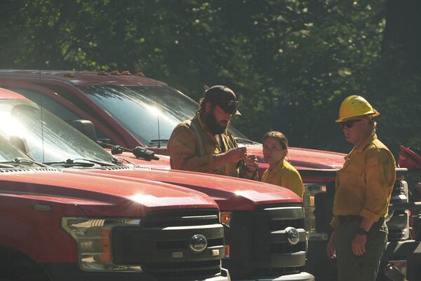 Idaho Department of Lands firefighters stand near a roadblock close to the scene the day after a shooter ambushed and killed multiple firefighters responding to a wildfire at Canfield Mountain Monday, June 30, 2025, in Coeur D'Alene, Idaho. (AP Photo/Lindsey Wasson)