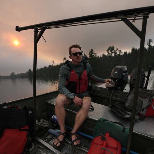 Willy Vosburgh, owner of Vosburgh's Custom Cabin Rentals on Moose Lake, uses a tow boat to evacuate canoeists from the Boundary Waters Canoe Area Wilderness after multiple wildfires burning there prompted its closure and evacuation Tuesday, July 14, 2026 in Ely, Minn. (Anthony Souffle/Minnesota Star Tribune via AP)