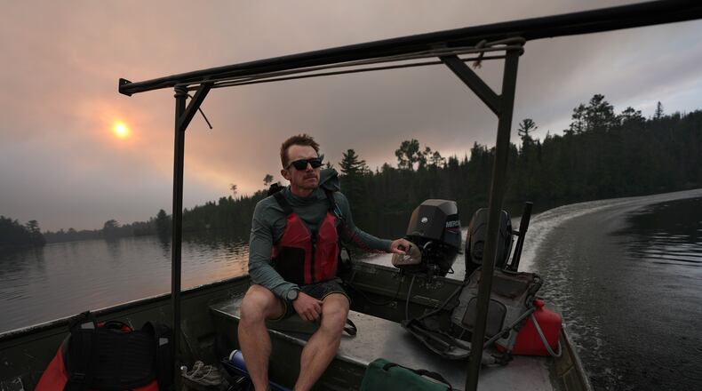 Willy Vosburgh, owner of Vosburgh's Custom Cabin Rentals on Moose Lake, uses a tow boat to evacuate canoeists from the Boundary Waters Canoe Area Wilderness after multiple wildfires burning there prompted its closure and evacuation Tuesday, July 14, 2026 in Ely, Minn. (Anthony Souffle/Minnesota Star Tribune via AP)