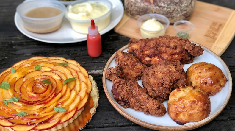 Takeout from Spring in Marietta: fried chicken dinner, with honey drop biscuits; braised greens; mashed potatoes; gravy and house-made hot sauce; peach tart and polenta sourdough. CONTRIBUTED BY WENDELL BROCK